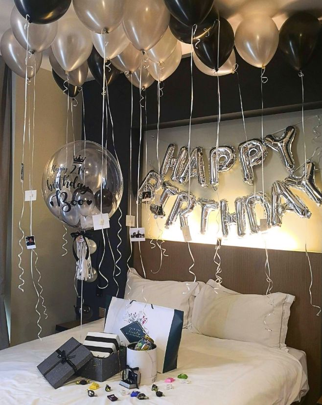 Hotel room with black, silver and gold balloons and a Happy Birthday banner