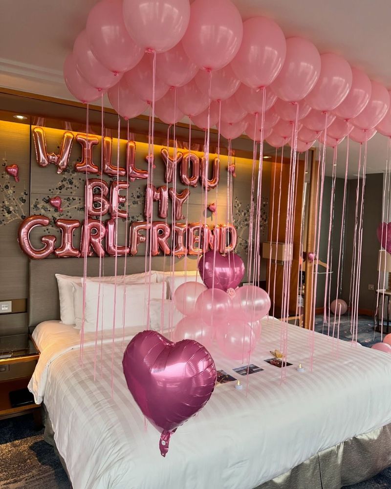 Hotel room decorated with pink balloons and a