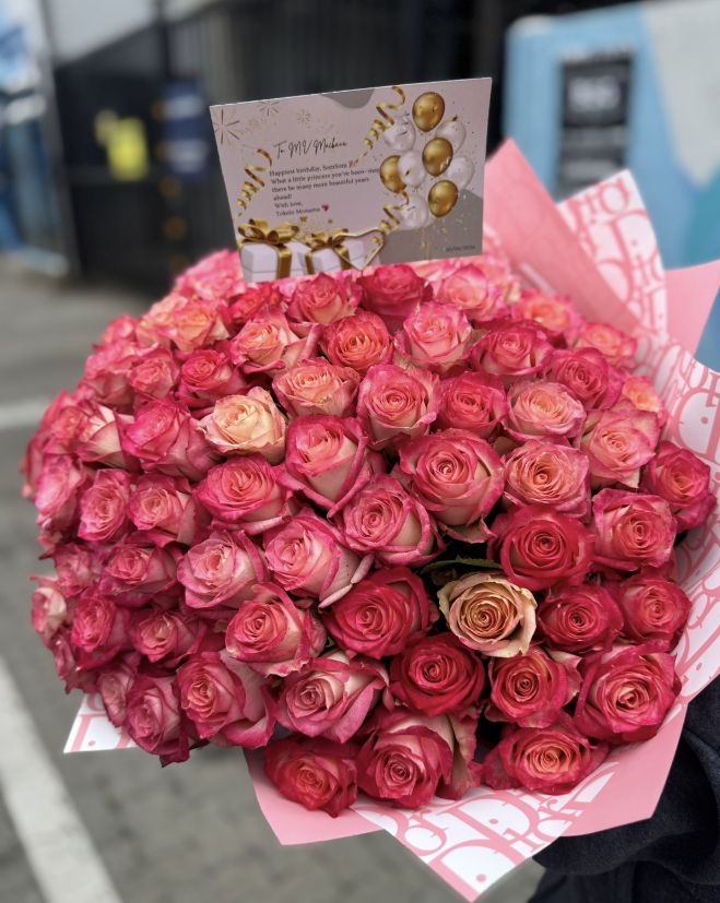 A bouquet of 100 pink and red roses in premium wrap with a birthday card